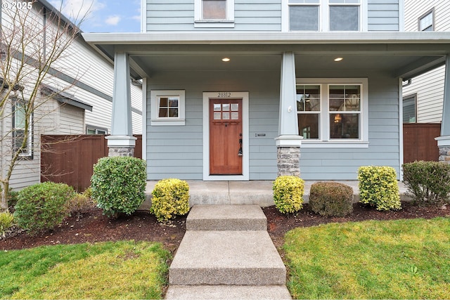 doorway to property with covered porch and fence