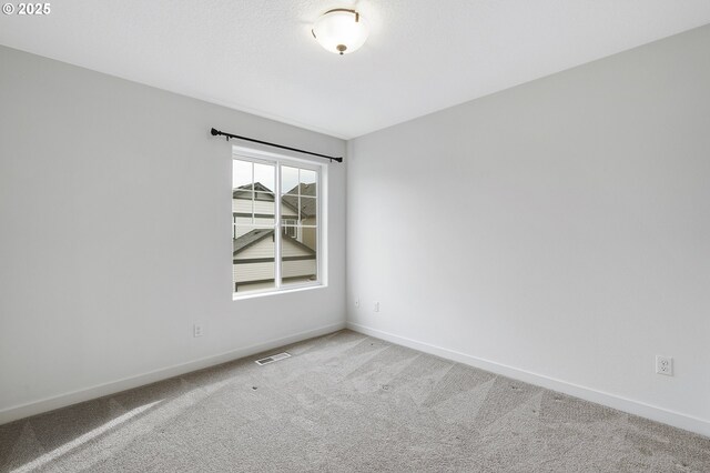 carpeted spare room with visible vents and baseboards