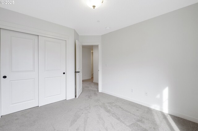 unfurnished bedroom featuring carpet floors, a closet, and baseboards