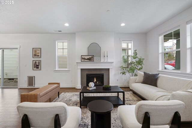 living room with recessed lighting, visible vents, a tiled fireplace, wood finished floors, and baseboards