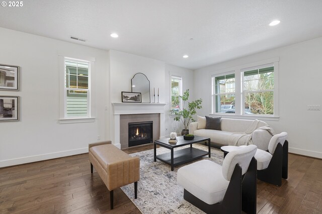 living area with recessed lighting, visible vents, a tile fireplace, baseboards, and hardwood / wood-style flooring