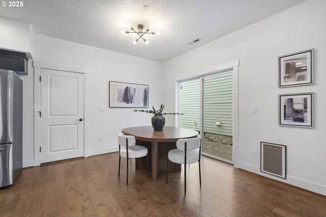 dining room with dark wood-style floors, visible vents, and a textured ceiling