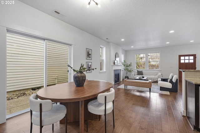 dining area featuring a fireplace, recessed lighting, visible vents, a textured ceiling, and hardwood / wood-style floors