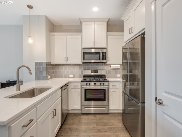 kitchen featuring stainless steel appliances, white cabinets, hanging light fixtures, and sink