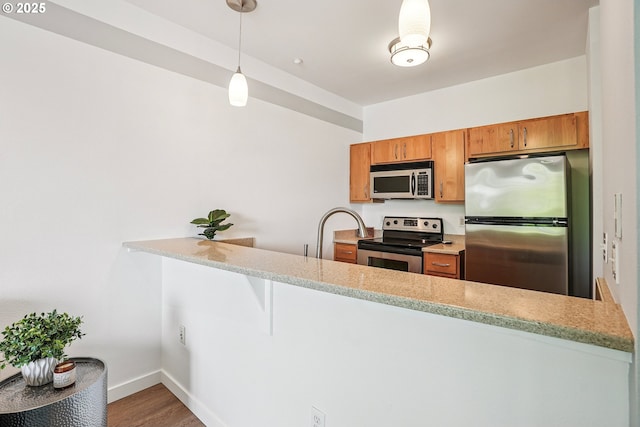1125 NW 9th Ave Unit 427, Portland, OR 97209 - kitchen featuring stainless steel appliances, a peninsula, wood finished floors, and brown cabinetry