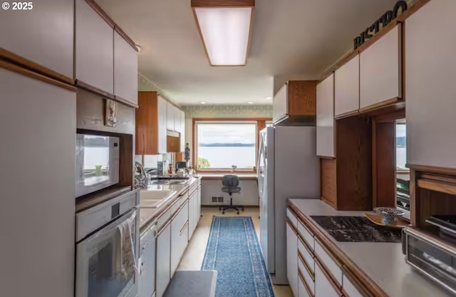 kitchen with white cabinetry, sink, and white appliances