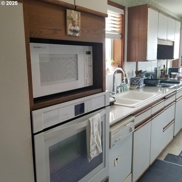 kitchen featuring sink, white appliances, and white cabinets