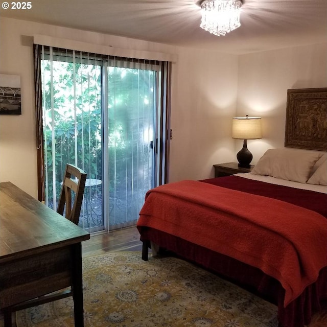 bedroom featuring an inviting chandelier, wood-type flooring, and access to exterior