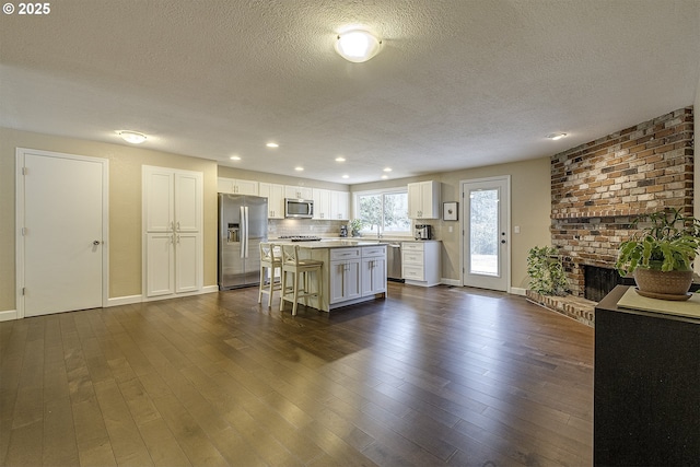 kitchen with dark wood finished floors, a kitchen island, white cabinetry, and stainless steel appliances