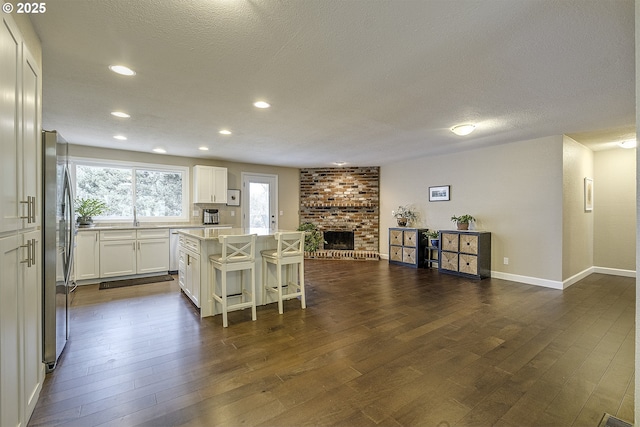 kitchen with a center island, a brick fireplace, stainless steel appliances, and dark wood-style flooring