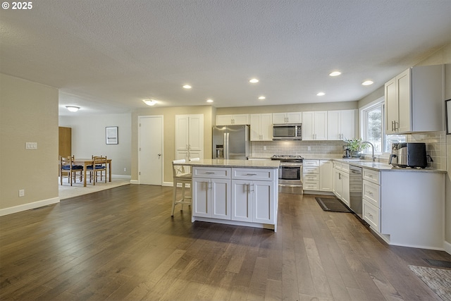 kitchen with backsplash, appliances with stainless steel finishes, dark wood-style floors, and a center island