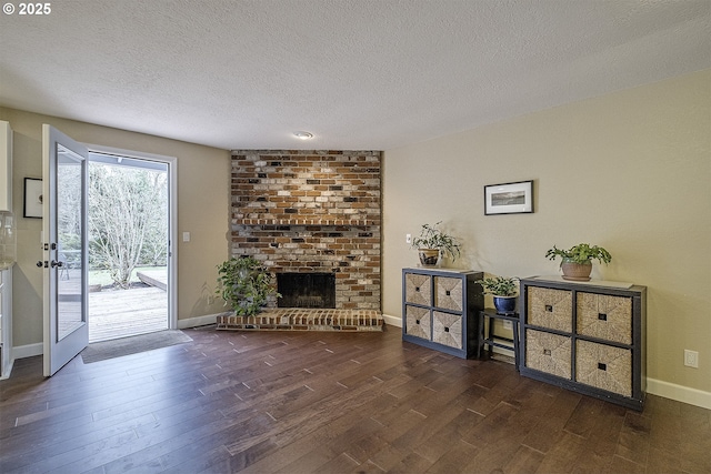 living area with a fireplace, a textured ceiling, baseboards, and wood finished floors