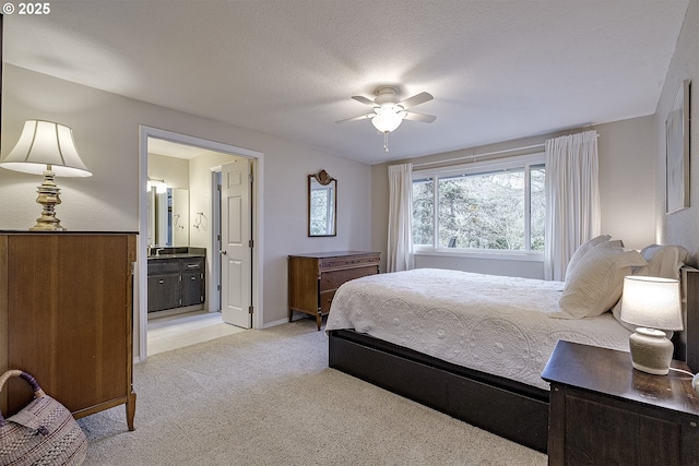 bedroom featuring a textured ceiling, light colored carpet, ensuite bathroom, and ceiling fan