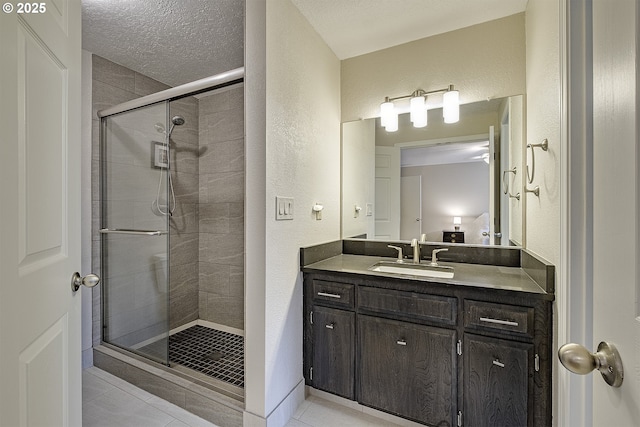 bathroom with tile patterned flooring, a shower stall, vanity, a textured wall, and a textured ceiling