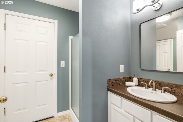 bathroom featuring tasteful backsplash, vanity, tile patterned flooring, and a shower with door