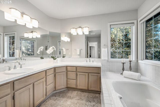 bathroom featuring a relaxing tiled tub and vanity