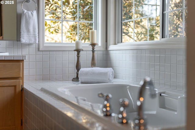 bathroom featuring a bath, vanity, a wealth of natural light, and decorative backsplash