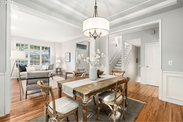 dining area featuring a notable chandelier, crown molding, and light wood-type flooring