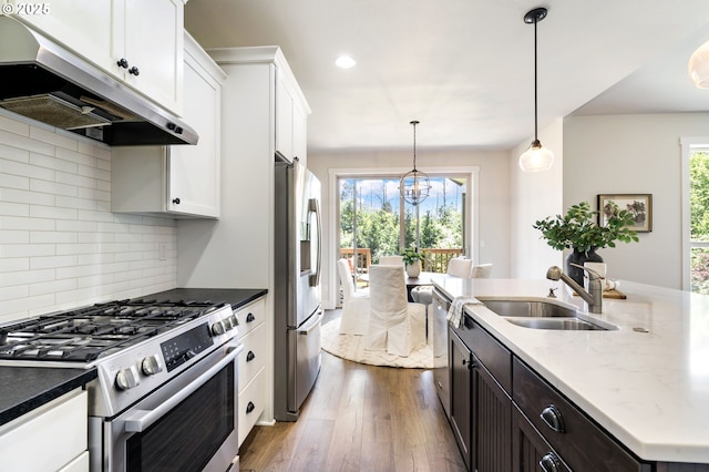 31870 SE Grace St, Gresham, OR 97080 - kitchen featuring appliances with stainless steel finishes, under cabinet range hood, dark wood finished floors, white cabinets, and tasteful backsplash
