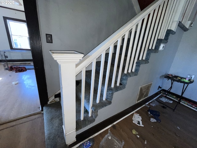 staircase featuring visible vents, baseboards, and wood finished floors