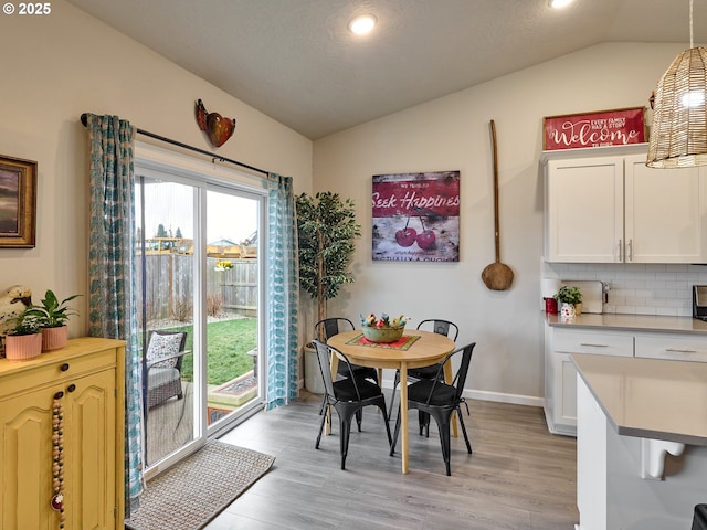 dining area with lofted ceiling and light hardwood / wood-style flooring