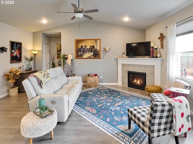 living room featuring hardwood / wood-style flooring, vaulted ceiling, ceiling fan, and a fireplace