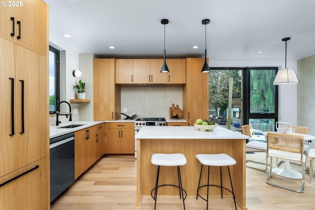 kitchen with dishwashing machine, sink, pendant lighting, stainless steel range, and a kitchen island