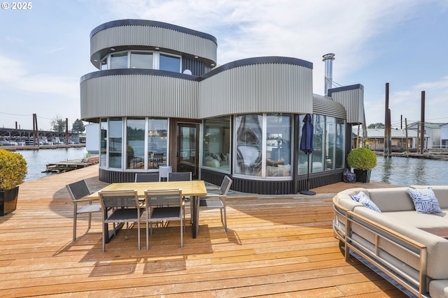 wooden terrace with a water view and outdoor dining area