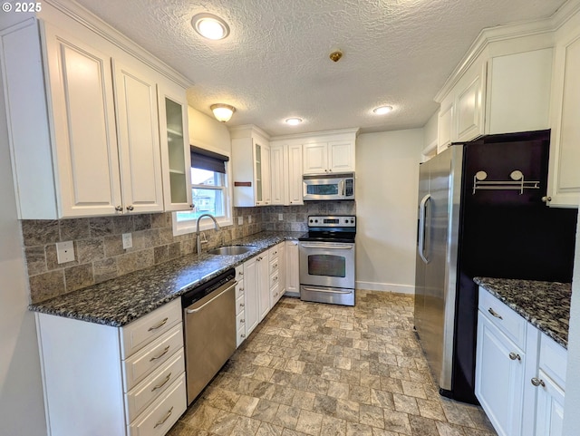 kitchen with a sink, tasteful backsplash, appliances with stainless steel finishes, white cabinets, and glass insert cabinets