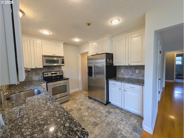 kitchen featuring backsplash, white cabinets, appliances with stainless steel finishes, and a sink