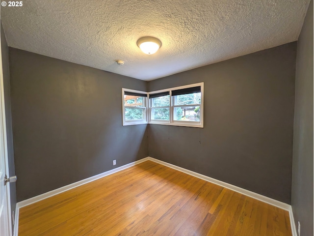 unfurnished room featuring light wood-style floors, baseboards, and a textured ceiling