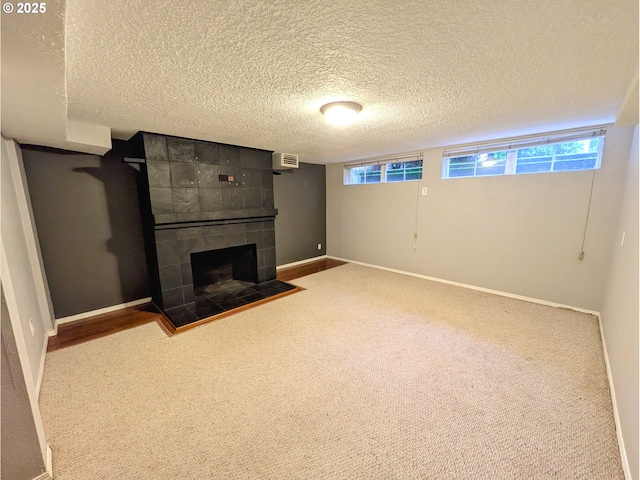 below grade area with a tiled fireplace, plenty of natural light, and baseboards