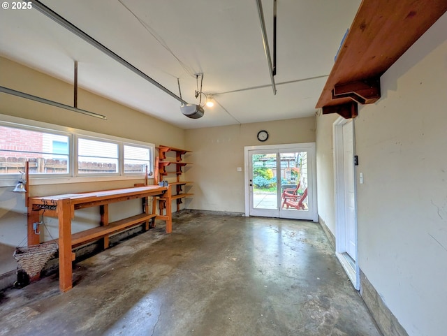 garage featuring a workshop area, a garage door opener, and baseboards