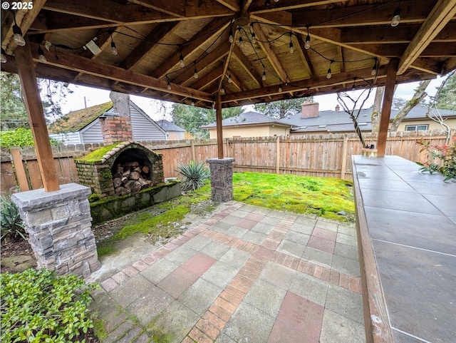 view of patio / terrace featuring a fenced backyard, a gazebo, and an outdoor brick fireplace