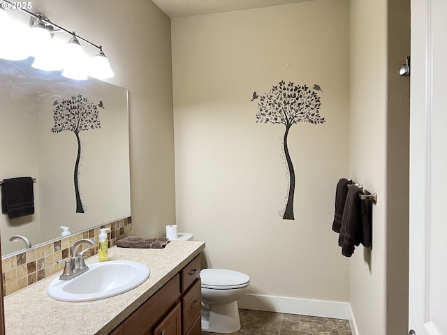 bathroom with vanity, toilet, tasteful backsplash, and baseboards