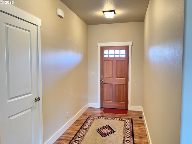 doorway featuring wood finished floors, baseboards, and a textured ceiling