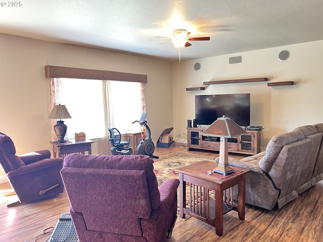 living room with ceiling fan, wood finished floors, and a textured ceiling