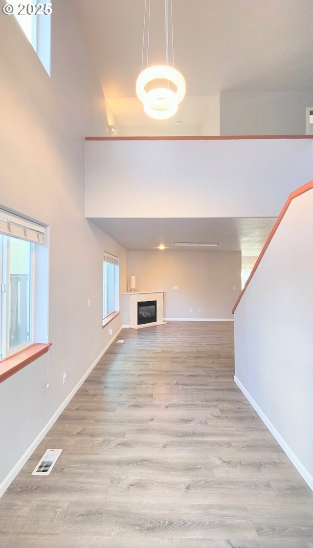 unfurnished living room featuring visible vents, wood finished floors, baseboards, and a glass covered fireplace