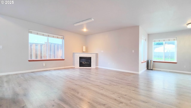 unfurnished living room featuring baseboards, wood finished floors, and a tile fireplace