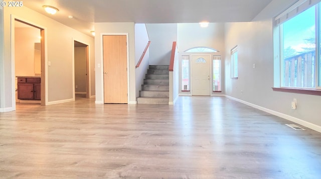 foyer featuring stairs, wood finished floors, a healthy amount of sunlight, and baseboards