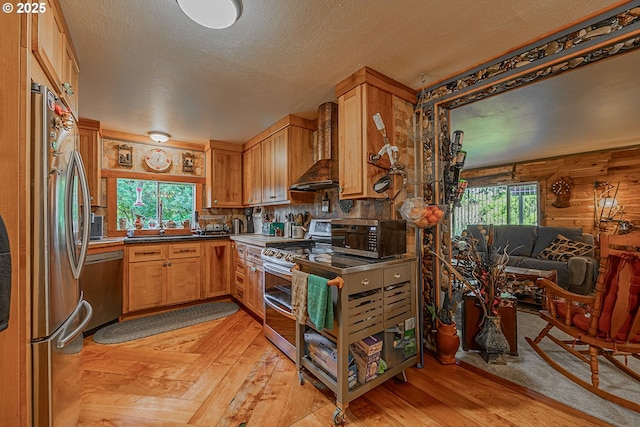 kitchen featuring sink, a textured ceiling, light wood-type flooring, appliances with stainless steel finishes, and custom range hood