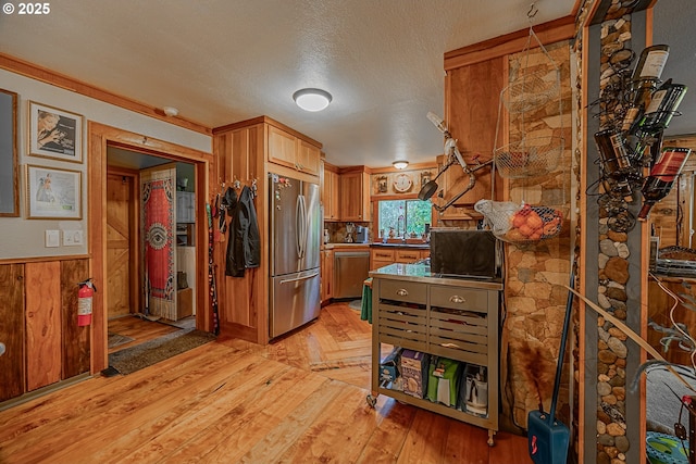 kitchen featuring appliances with stainless steel finishes, sink, light hardwood / wood-style floors, and a textured ceiling