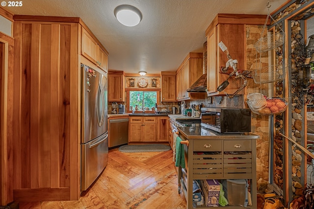 kitchen featuring wall chimney exhaust hood, appliances with stainless steel finishes, kitchen peninsula, and a textured ceiling