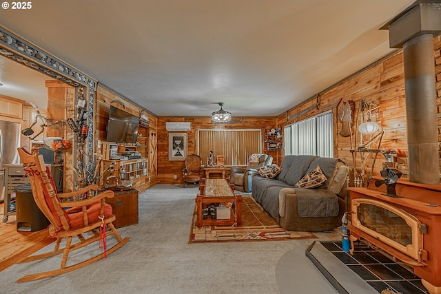 carpeted living room with a wood stove, a wall mounted air conditioner, and wood walls