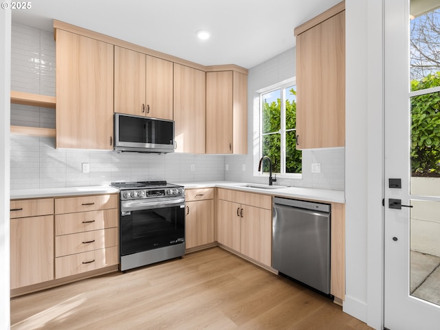 kitchen with appliances with stainless steel finishes, sink, and light brown cabinets