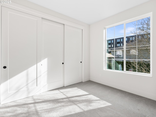 unfurnished bedroom with light carpet and a closet