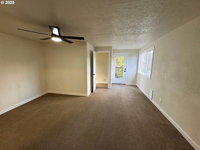 unfurnished room with a textured ceiling, a textured wall, visible vents, baseboards, and dark carpet