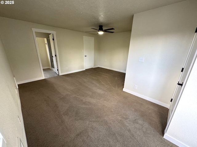 empty room featuring a textured ceiling, dark colored carpet, ceiling fan, and baseboards