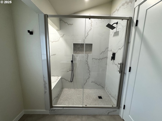 full bath featuring a shower stall, baseboards, and vaulted ceiling