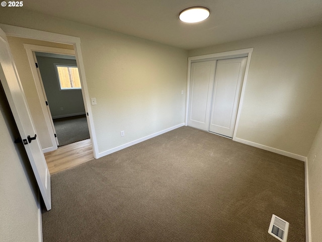 unfurnished bedroom with carpet, a closet, visible vents, and baseboards